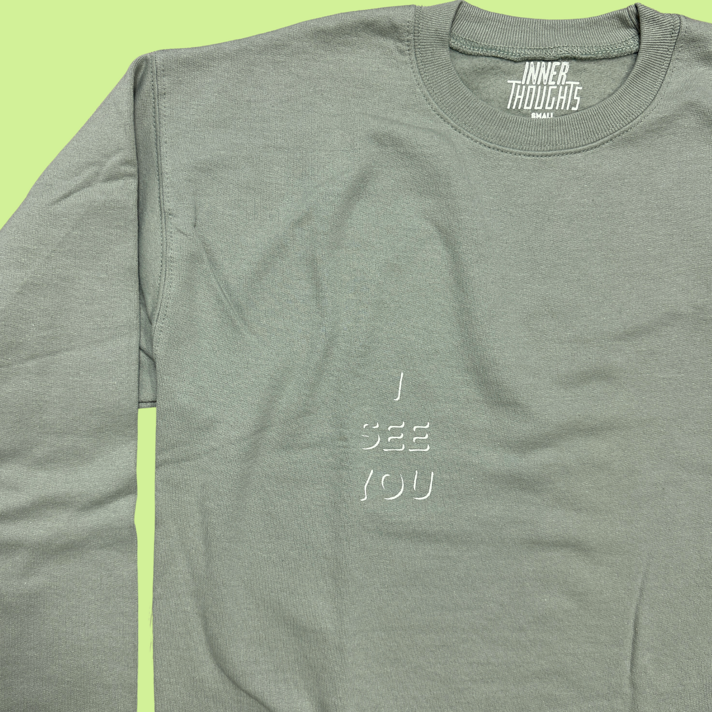 closeup Sage Green Crewneck Sweatshirt with white "I See You" design on the left pocket area