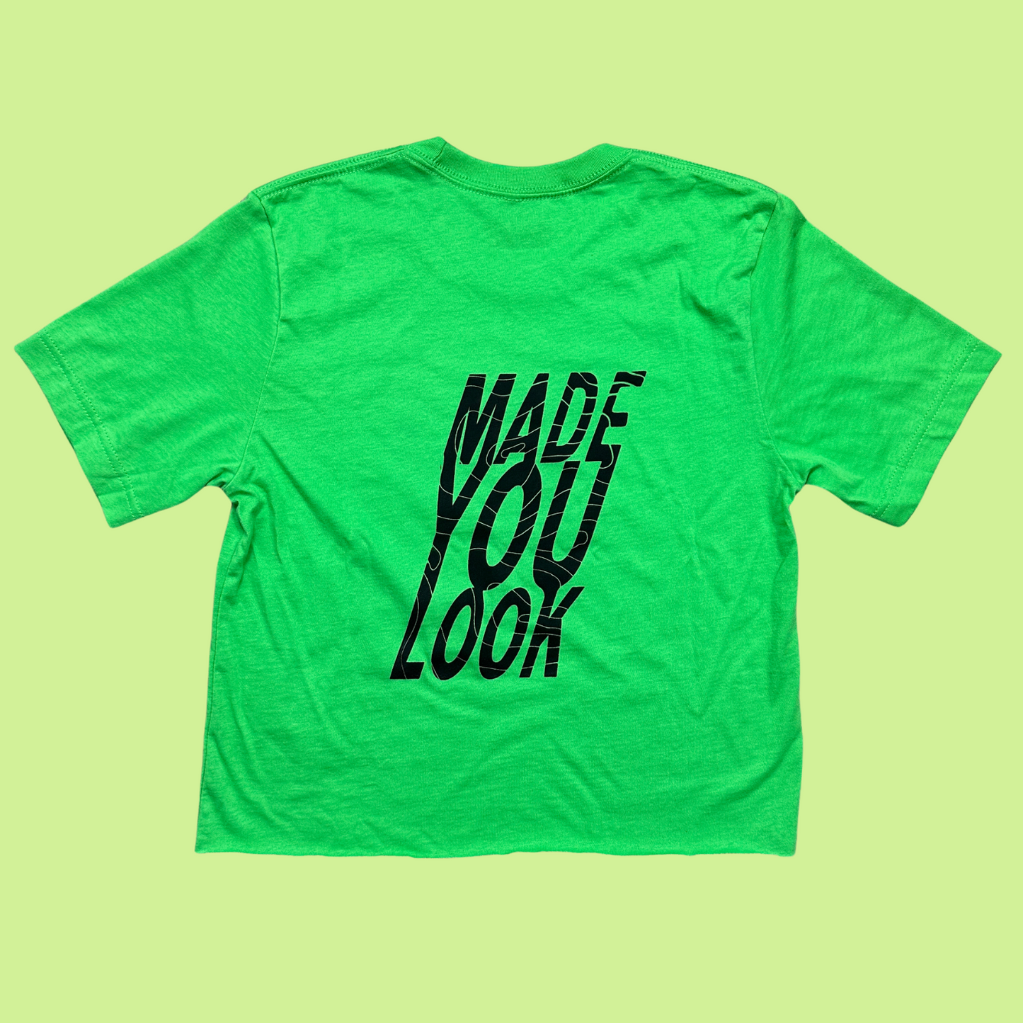 Back of the bright green cropped tee with "made you look" in big block letters with a line that runs through all the words. The design is black.