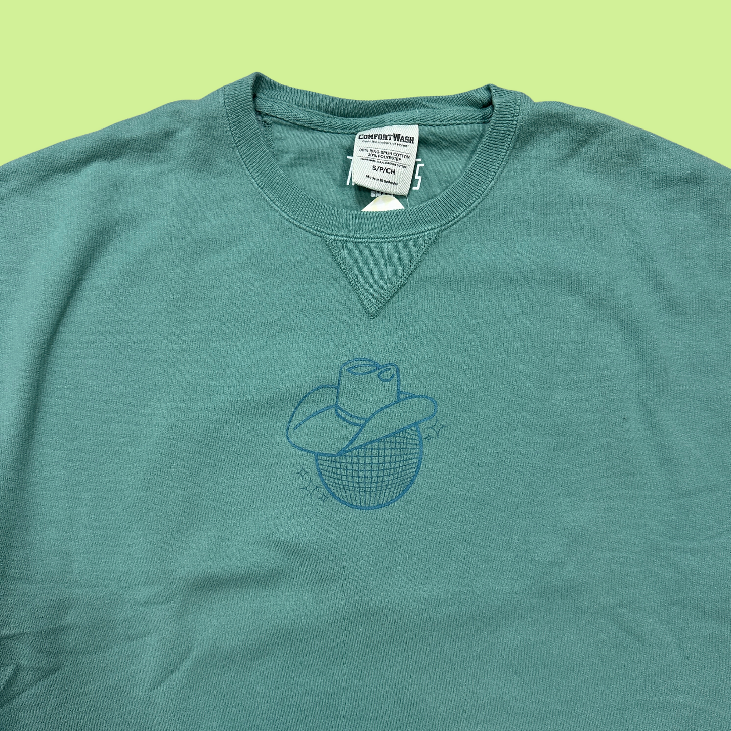 closeup - cyprus green crewneck sweatshirt with a disco ball in a cowboy hat printed on the front in a teal blue color