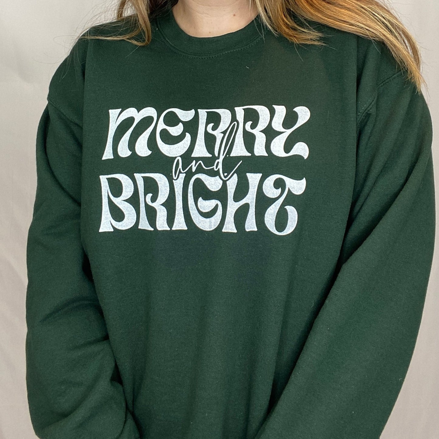 Dark Green Crewneck Sweatshirt with "merry and bright" printed on the front in white