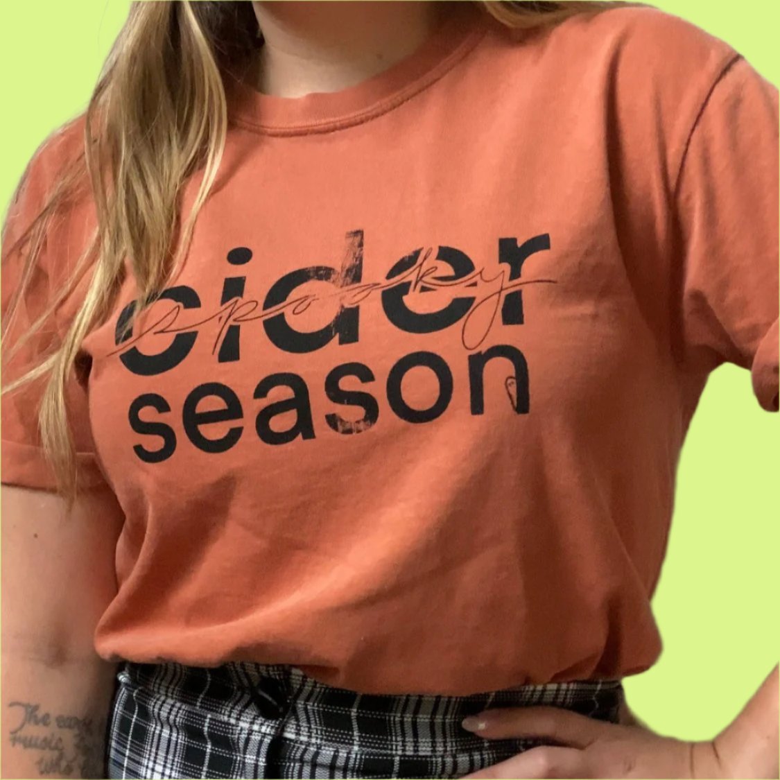Girl wearing cider/spooky season shirt with black and white plaid pants