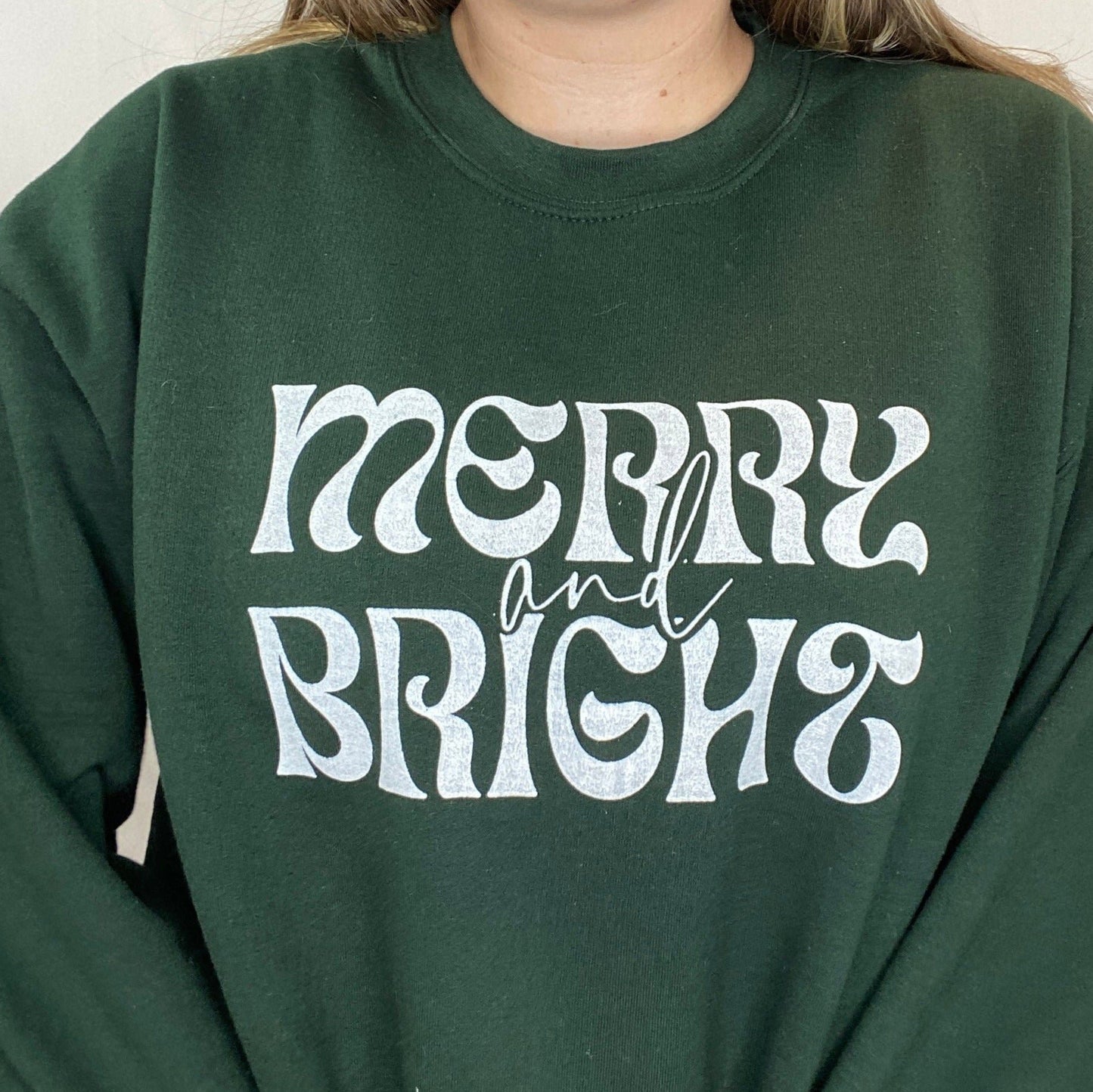 Dark Green Crewneck Sweatshirt with "merry and bright" printed on the front in white